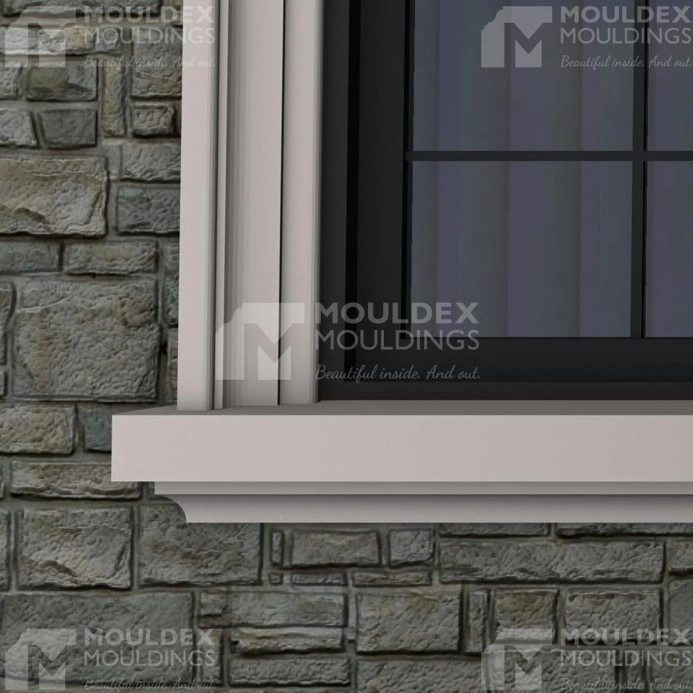 Close-up composite window with a white, multi-stepped composite surround and sloped sill on a grey stone facade by Mouldex.