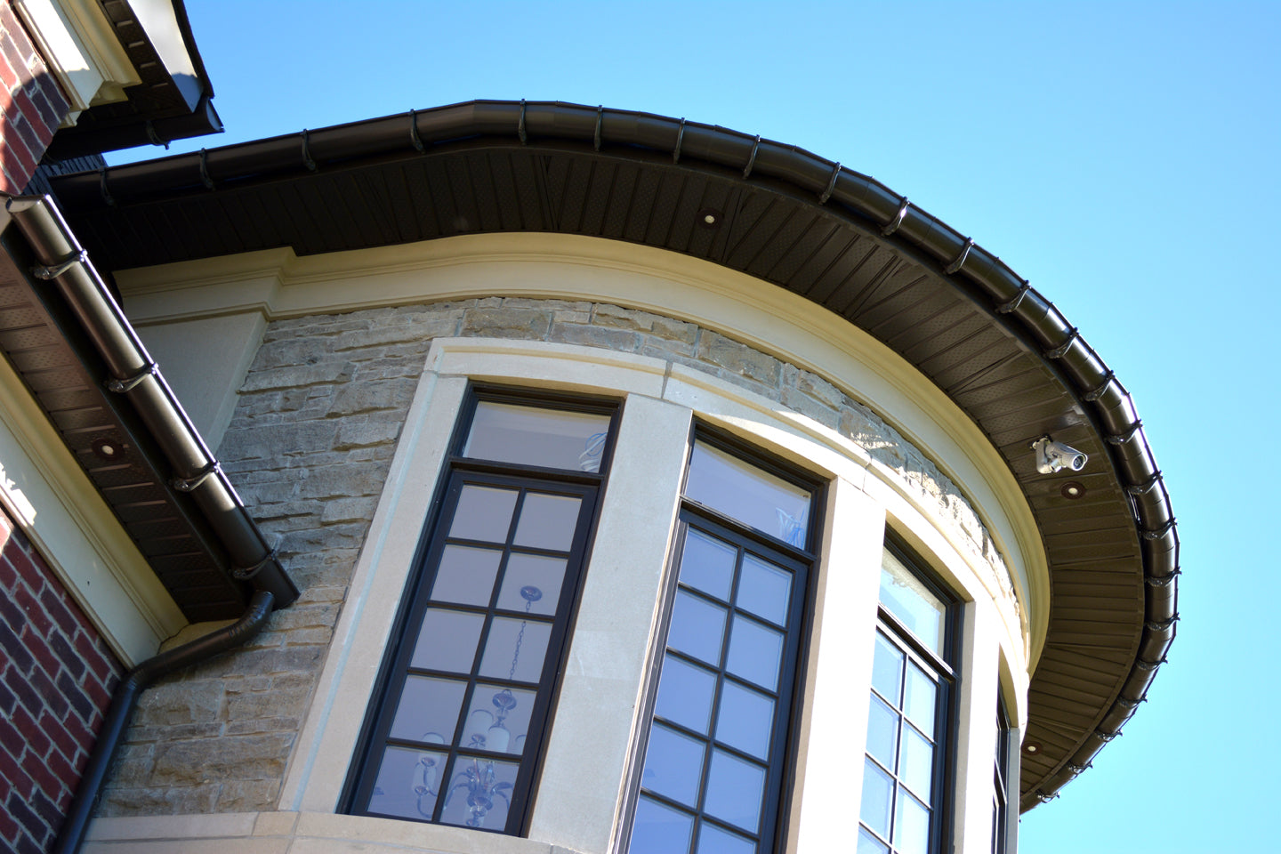 Close-up of a curved stone residential exterior featuring custom cement-coated foam cornice mouldings and window trim.