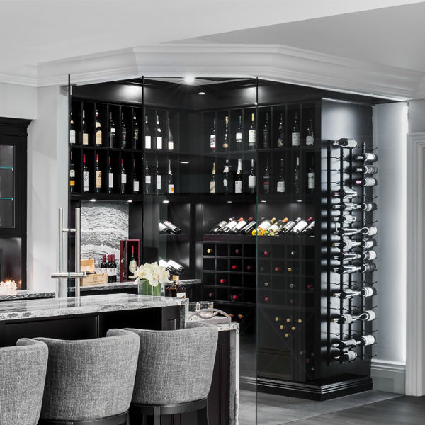 Modern basement bar and glass-enclosed wine cellar from "Moving the McGillivrays" featuring custom white plaster-coated crown moulding by Mouldex Composites above black cabinetry.