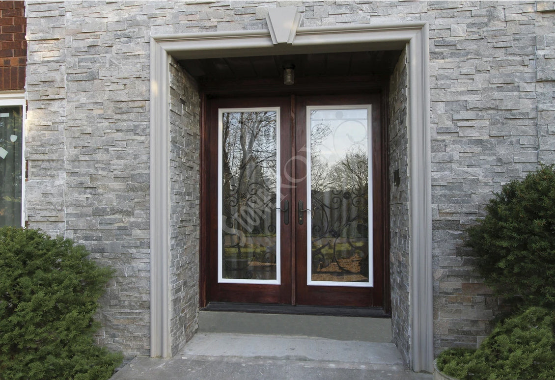 Modern residential entrance featuring natural stone panel wall accents and a custom cement-coated foam door surround with a decorative keystone by Mouldex Composites.