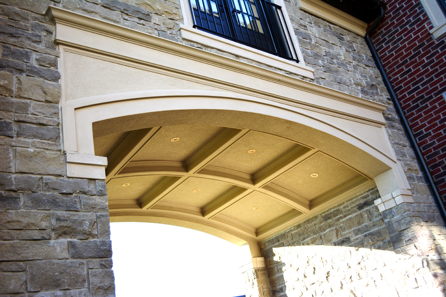 Grand residential stone portico featuring a custom-engineered arched header and matching ceiling grid mouldings.
