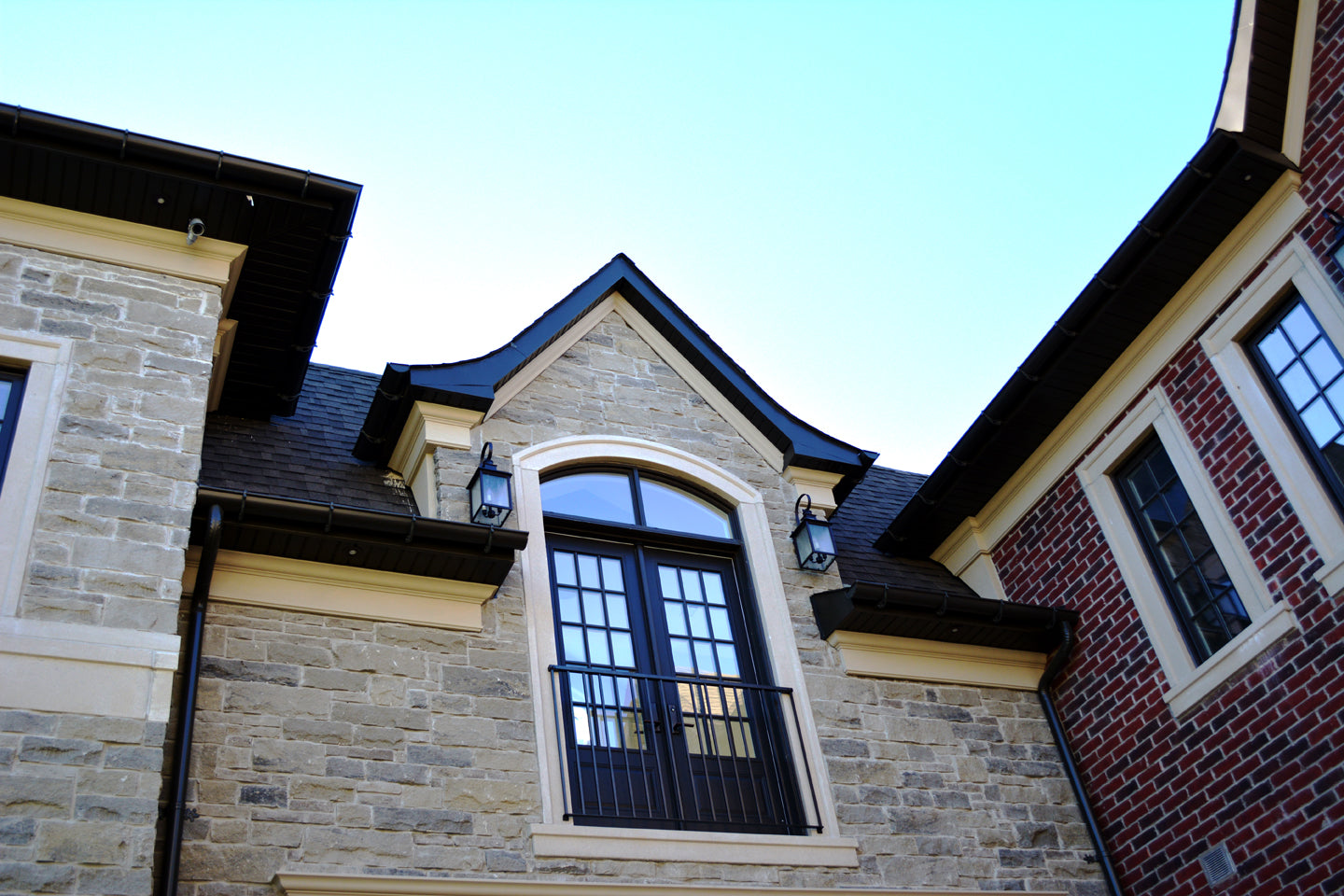 Custom residential exterior featuring arched window headers and matching architectural trim on a mixed stone and brick facade.